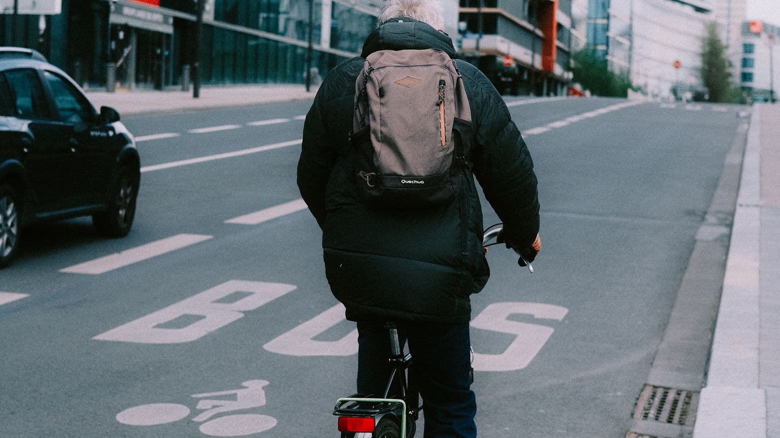 Cycliste avec un sac à dos sur une bande cyclable urbaine